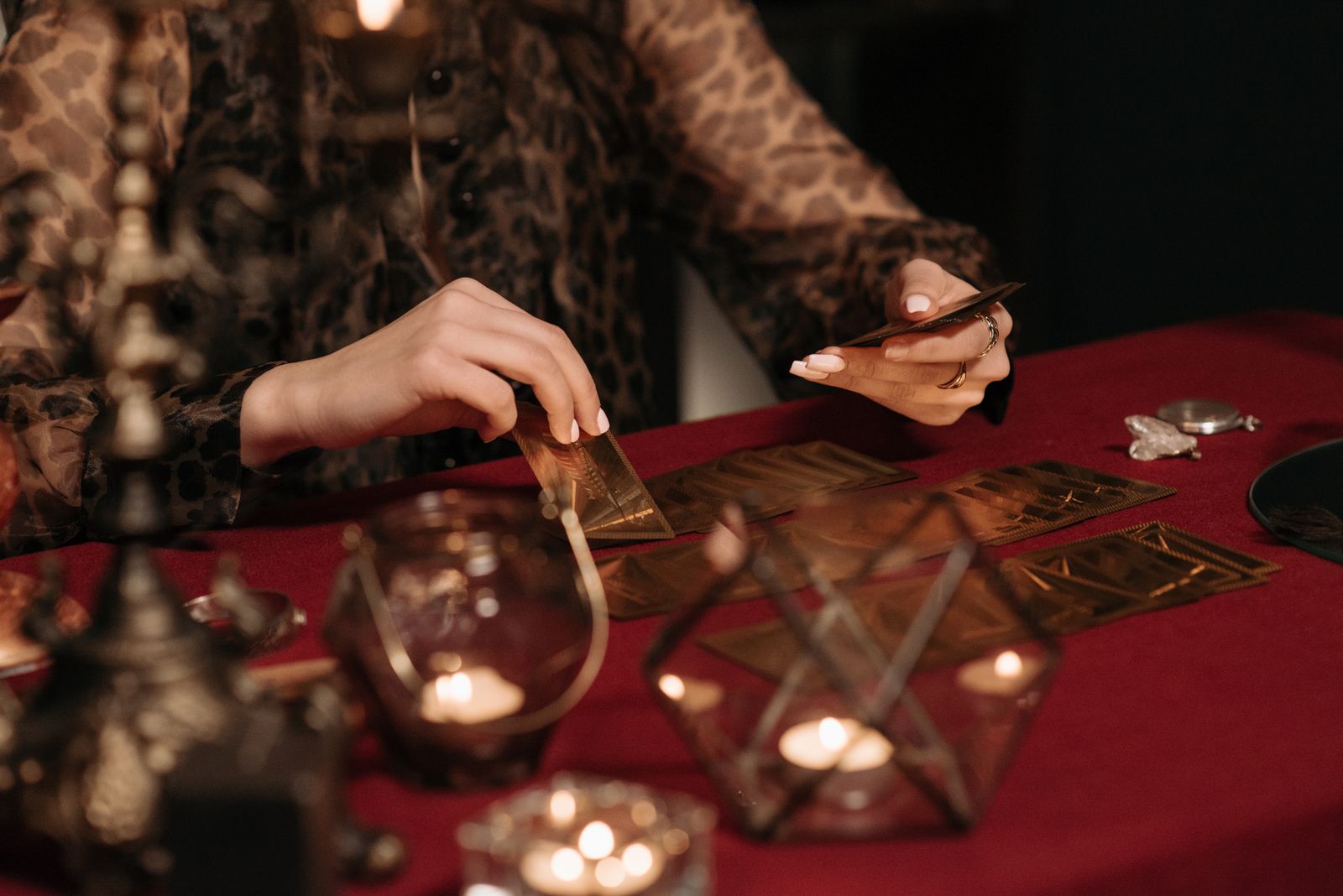 Leitura de cartas numa mesa vermelha iluminada por velas