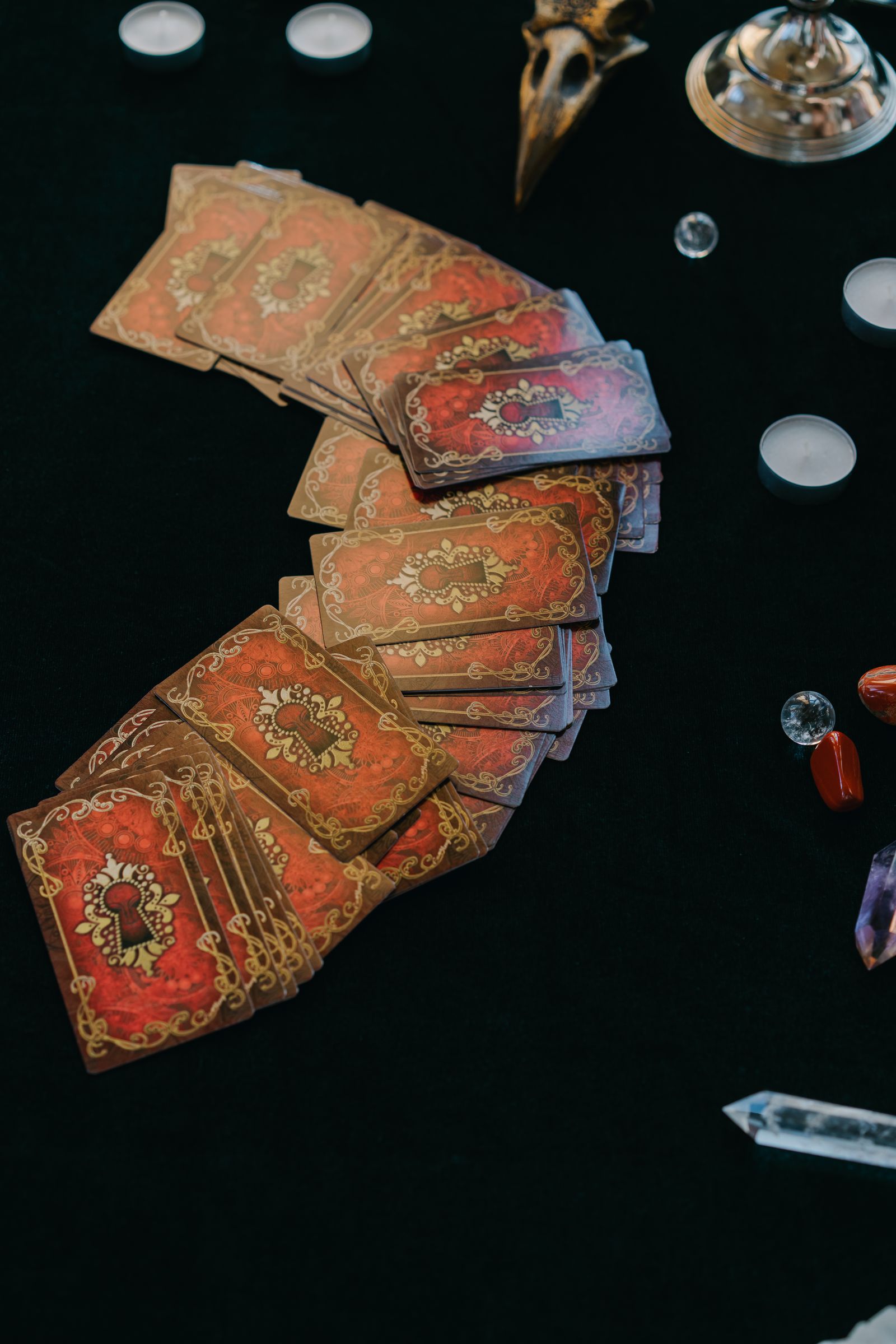 Cartas de tarot dispostas sobre tecido negro com velas e cristais